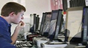 Joven frente a computadora en cibercafé o sala de conexión pública a internet