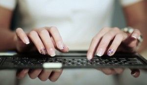 Detalles de manos de mujer escribiendo en teclado de computadora