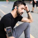 Hombre con audífonos Bluetooth y smartphone