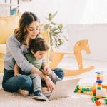 Mamá con hijo y computadora en sala de su casa