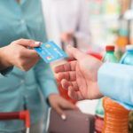 Mujer que da tarjeta de crédito al cajero